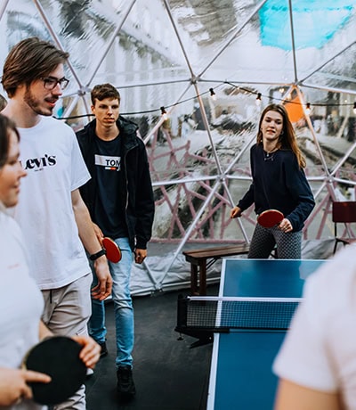 Gezellig pingpongspel onder een glazen koepel tijdens een breedjaar evenement bij Breekjaar, geschikt voor teambuilding en recreatie in een unieke locatie.